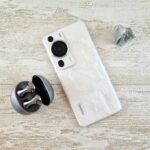 A stylish white smartphone and wireless earbuds on a textured surface for tech enthusiasts.